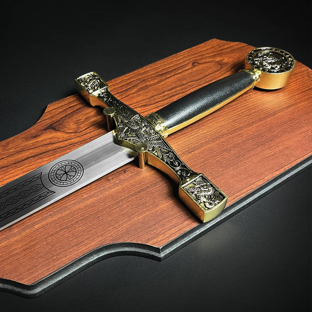 Decorative Excalibur Medieval sword with detailed gold hilt and black handle on wooden display plaque