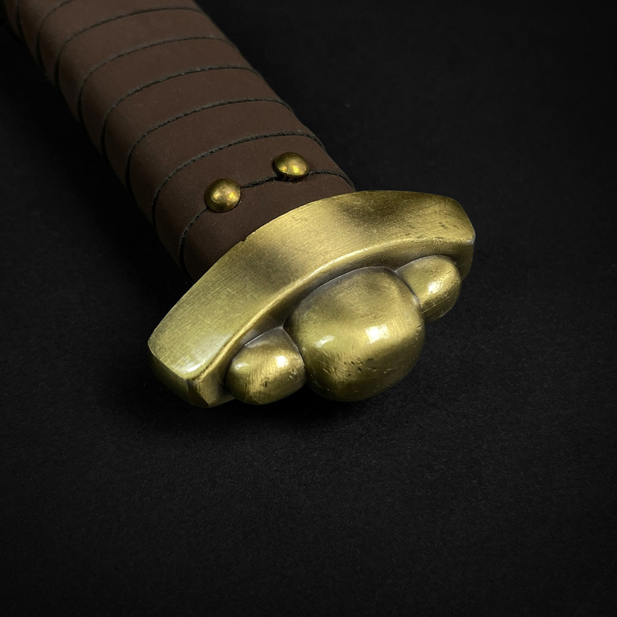 Close-up of the hilt of Knights Collection Godfrid the Battle-Born Viking Sword with a bronze guard and leather grip.