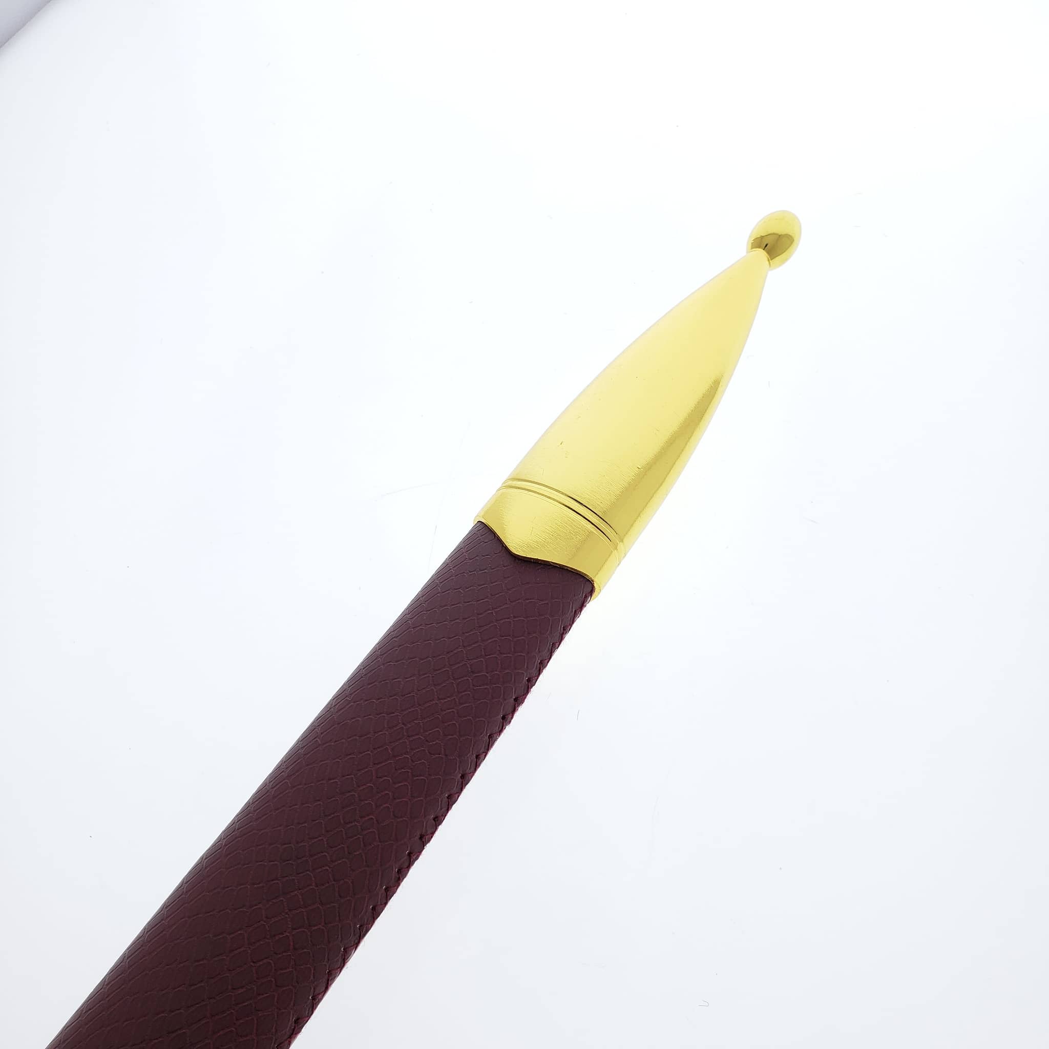 Close-up of medieval one hand sword sheath tip with gold-colored metal cap and brown textured leather